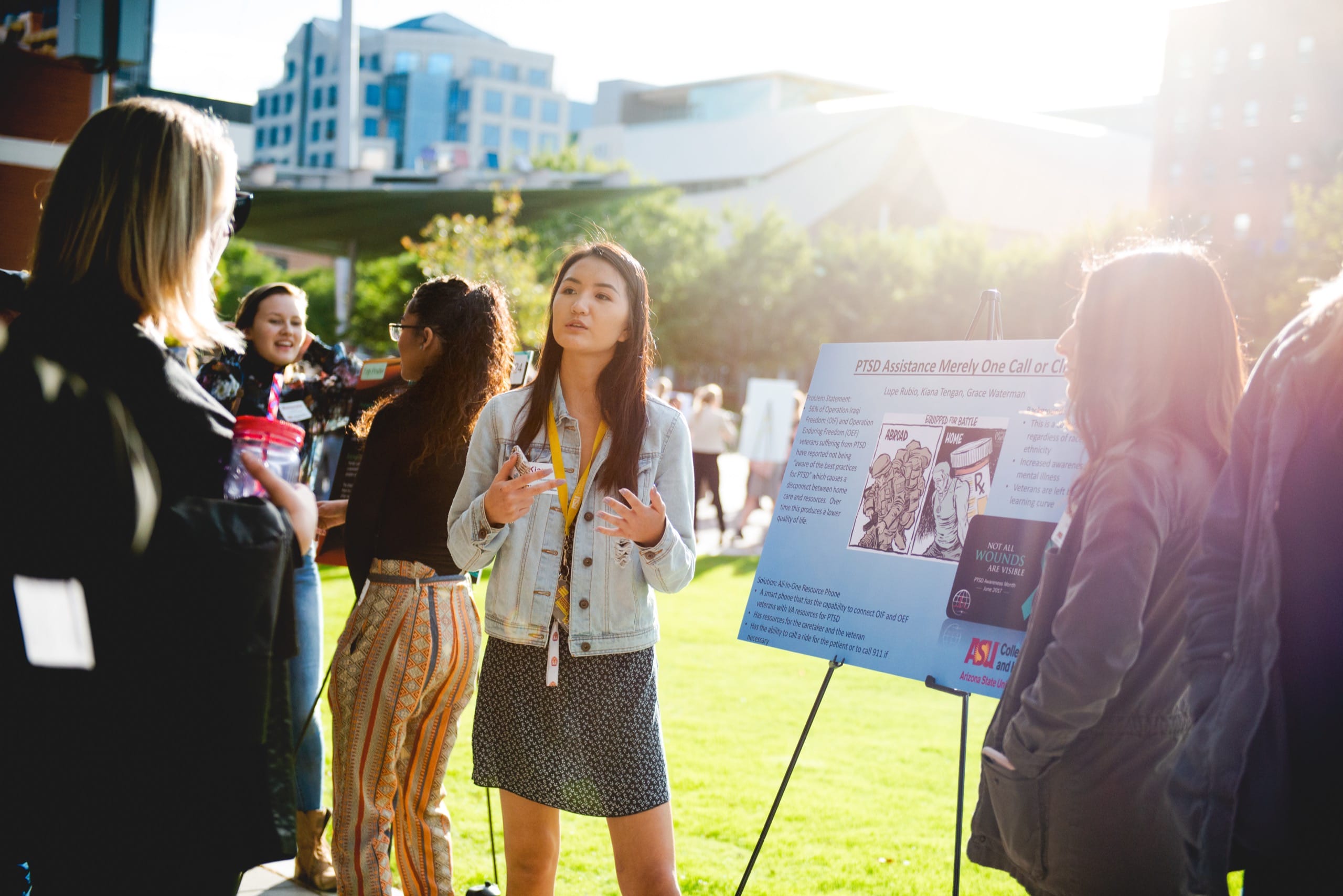 Woman in front of poster talking to people