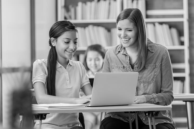 Teacher sitting at desk with student