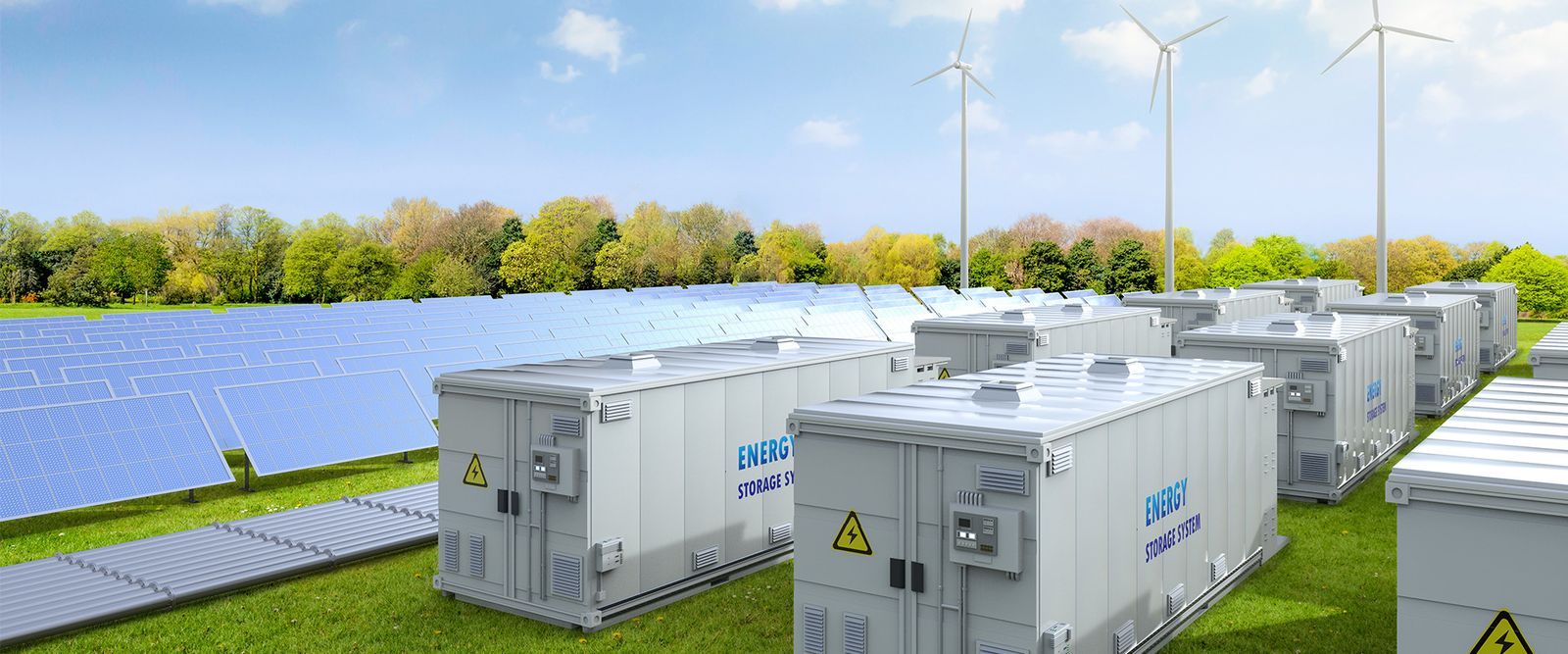 Large white modular energy storage battery containers lined up in a field alongside solar panels and wind turbines under a blue sky.